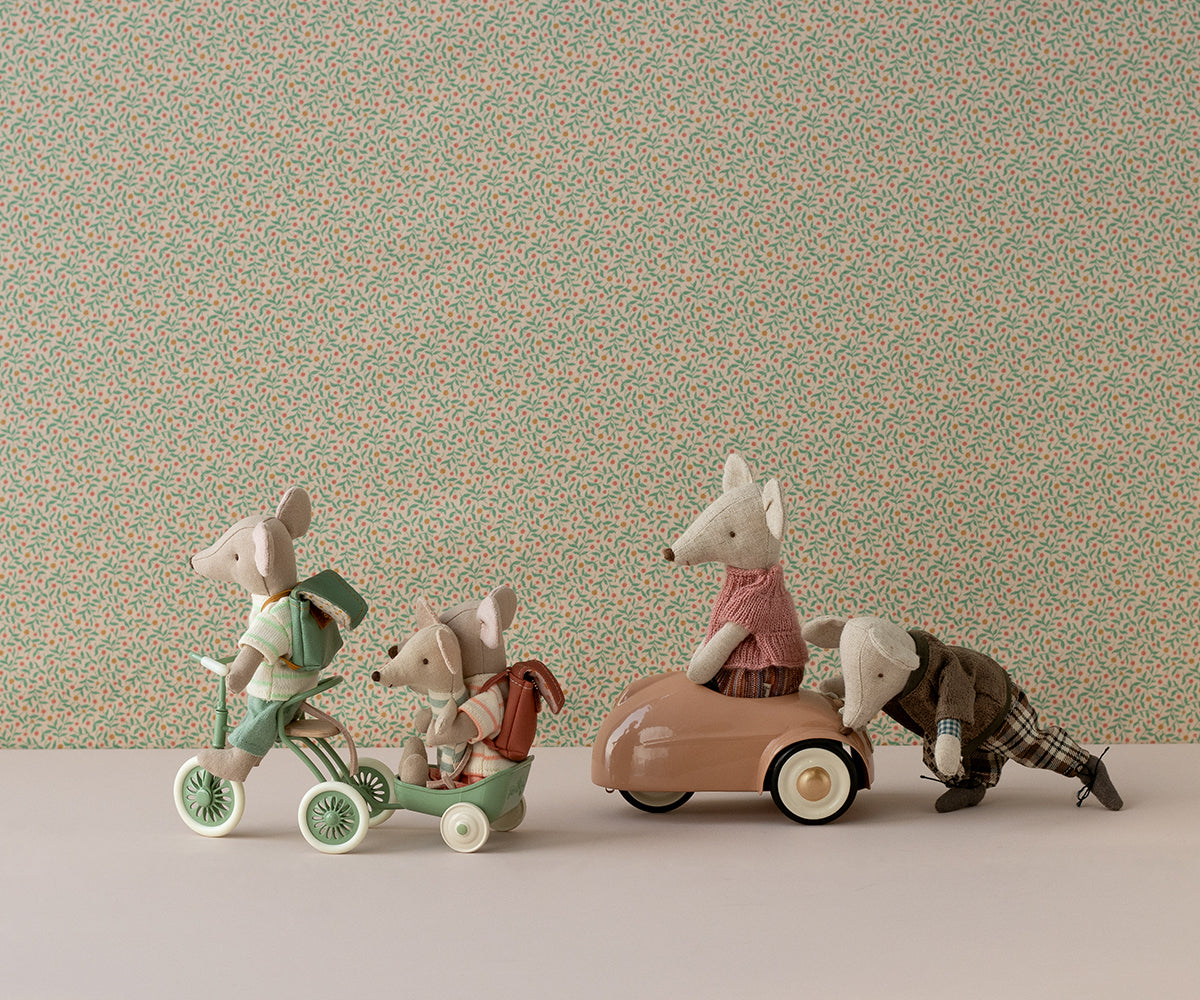 Maileg mice on a green tricycle and in a pink mouse car, with Dad mouse pushing