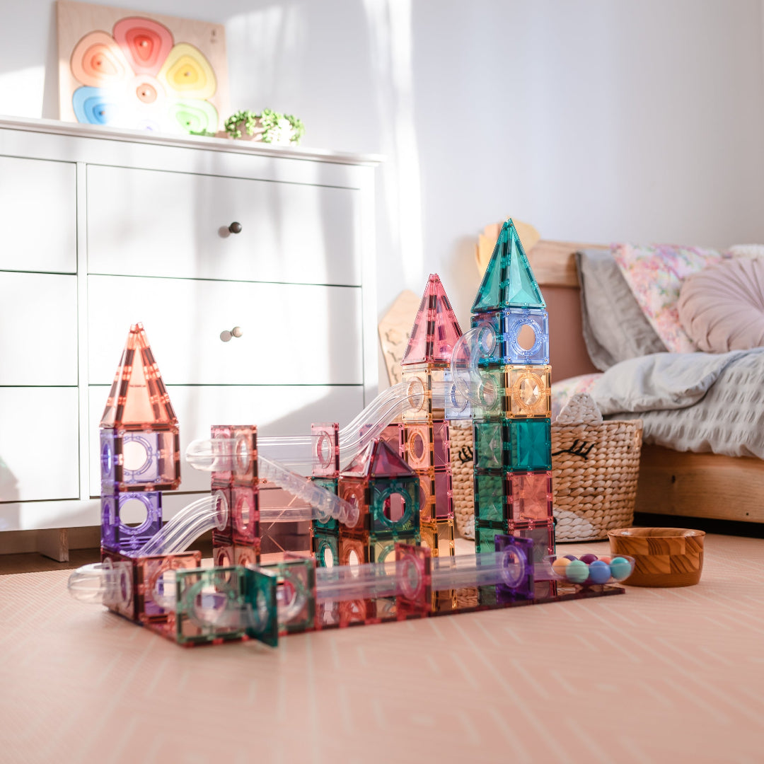 Pastel CONNETIX ball run built from magnetic tiles on a wooden bedroom floor