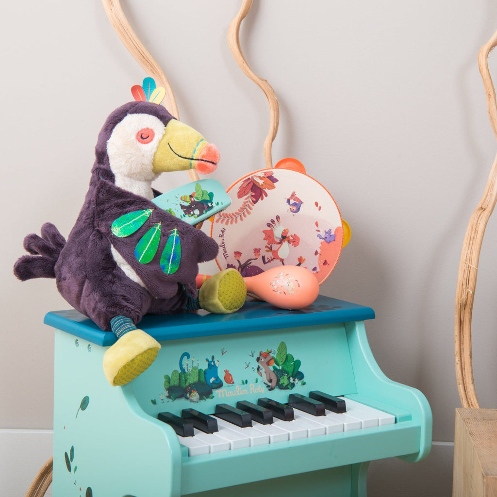 Children's toy piano with a plush toucan toy on top against a neutral background
