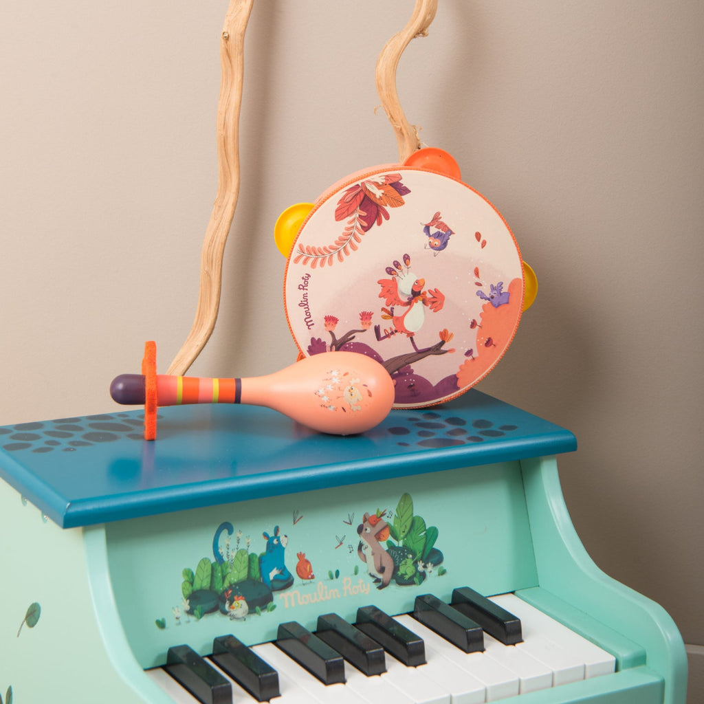 Children's toy piano with maraca and tambourine on a beige background