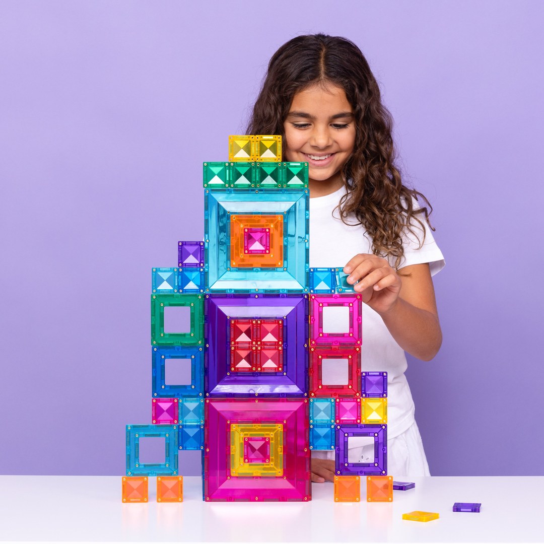 Smiling girl building a tall rainbow tower with CONNETIX portal tiles