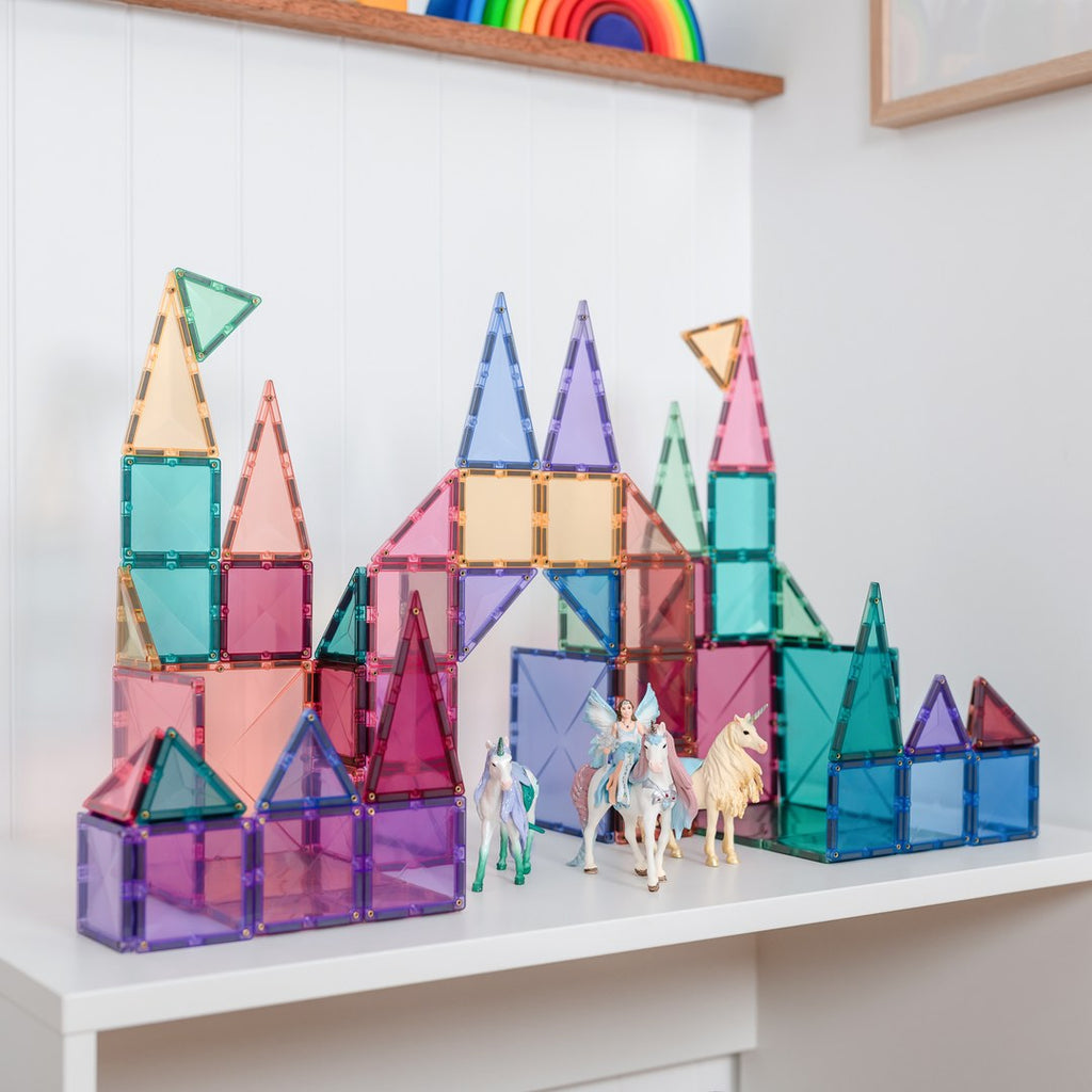 Pastel CONNETIX magnetic tile castle with toy unicorns and a fairy on a white shelf