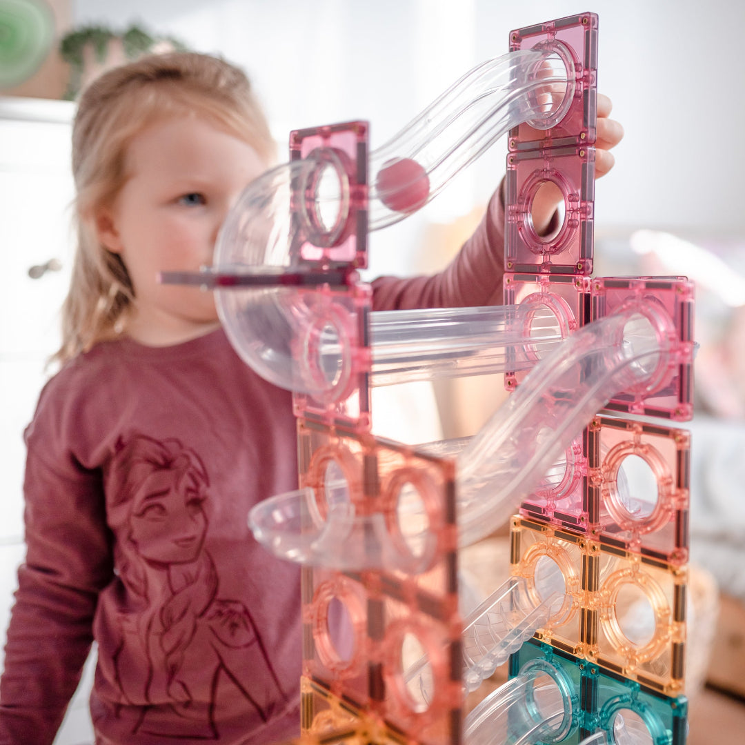 Child playing with a pink and clear CONNETIX pastel ball run
