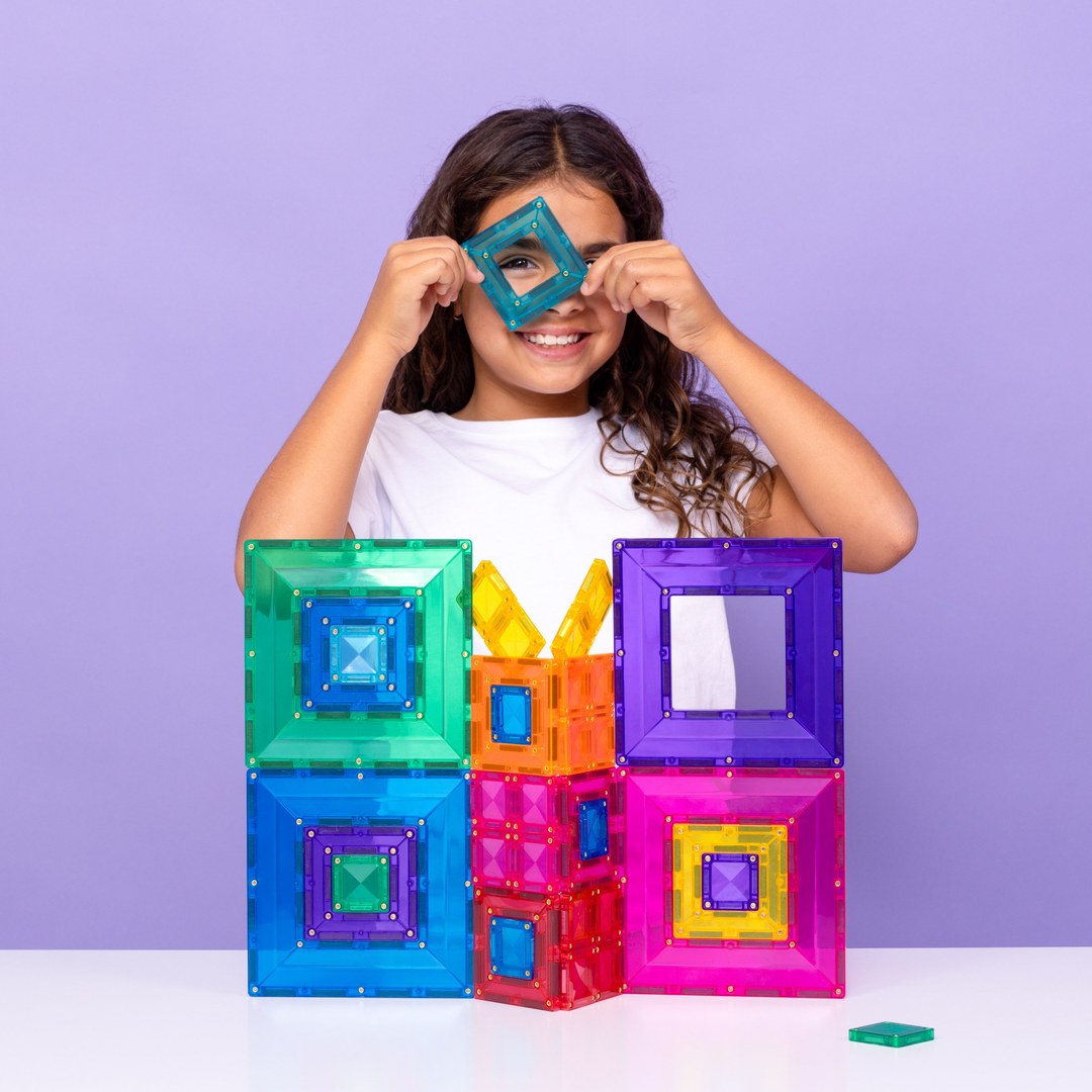Girl peeking through a CONNETIX portal tile beside a nested rainbow build
