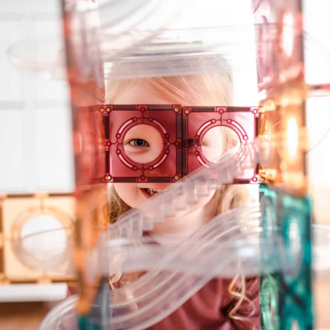 Child peeking through a pastel CONNETIX magnetic tile ball run