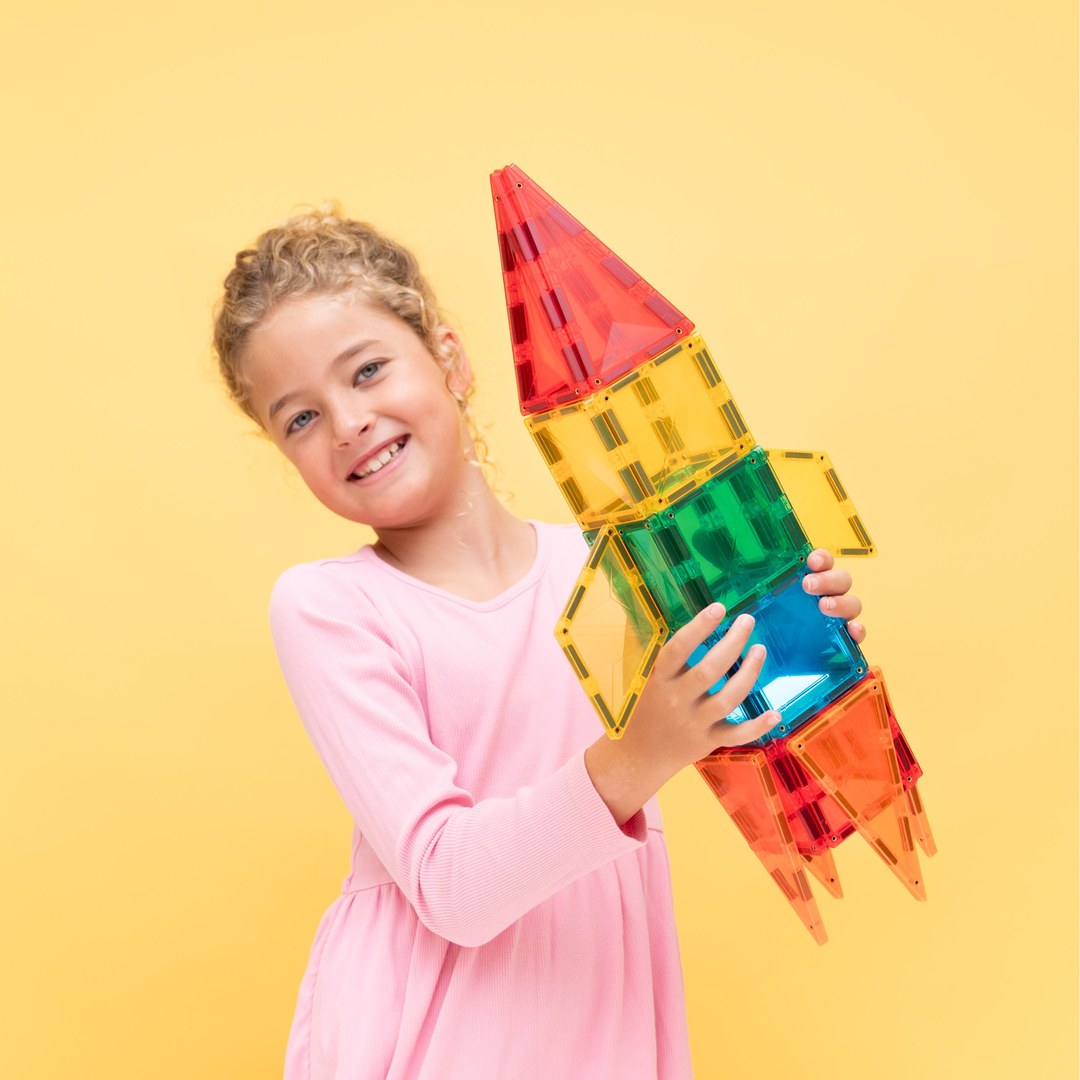 Happy girl holding up a colourful rocket built with the CONNETIX Light Rocket Pack