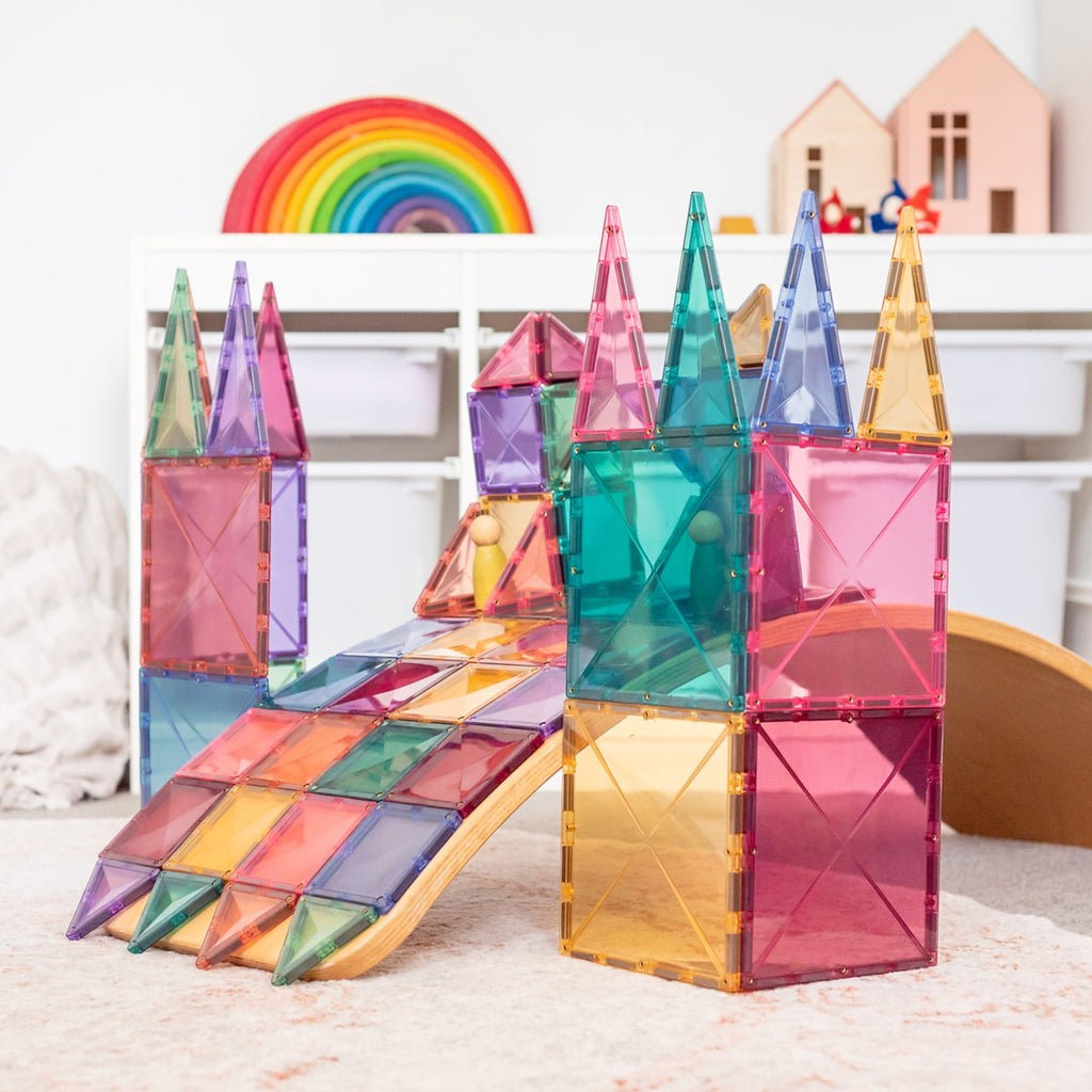 Pastel CONNETIX magnetic tile castle towers with a tiled ramp over a wooden balance board