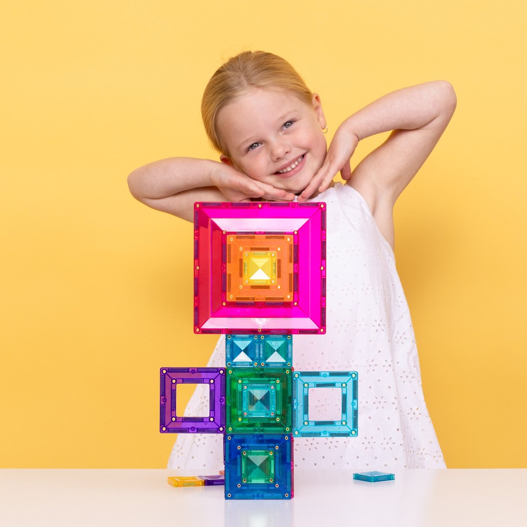 Smiling girl holding nested pink, orange and yellow CONNETIX portal tiles