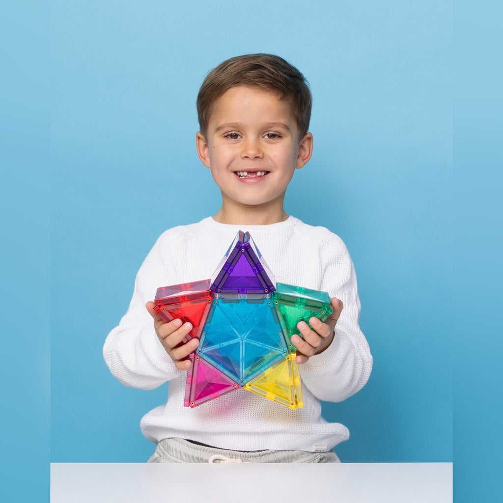 Smiling boy holding a rainbow star built with the CONNETIX Light Star Pack