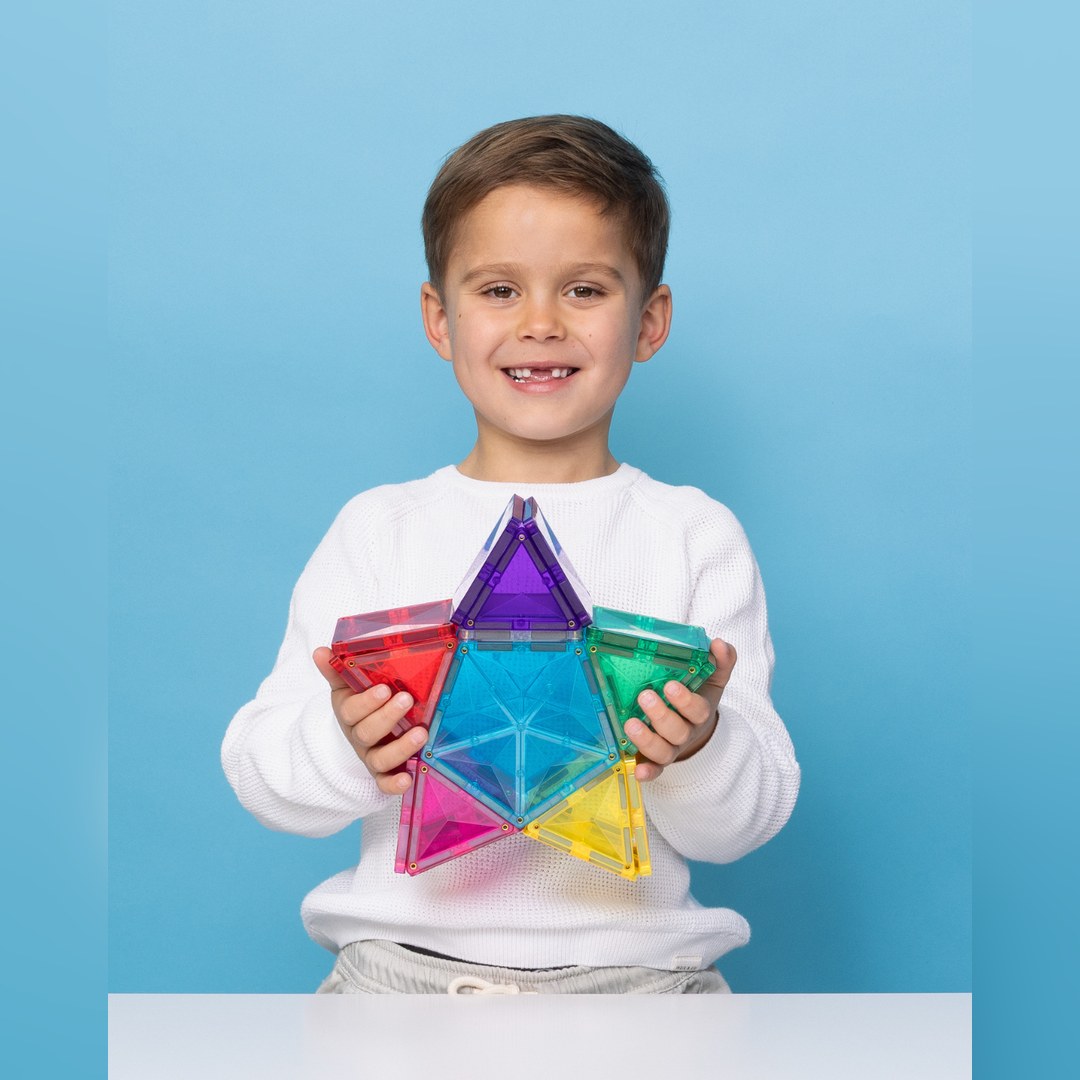 Smiling boy holding a rainbow star built with the CONNETIX Light Star Pack