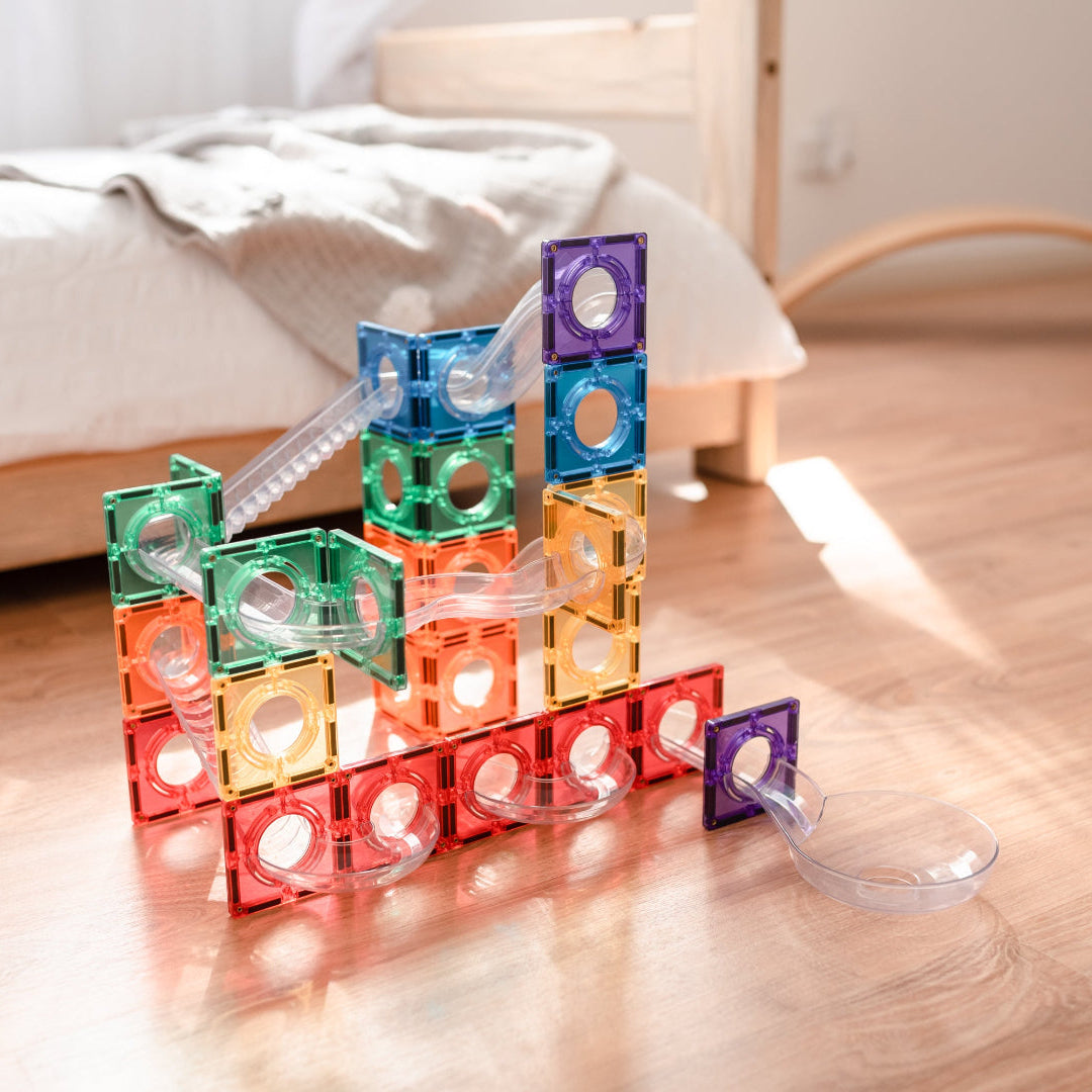Rainbow CONNETIX ball run with clear tubes built on a wooden bedroom floor