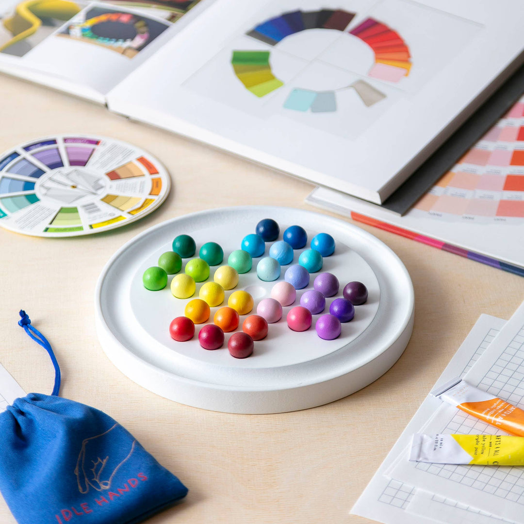 Block Design Gradient Solitaire, a round wooden peg solitaire board with 33 rainbow colour wheel balls