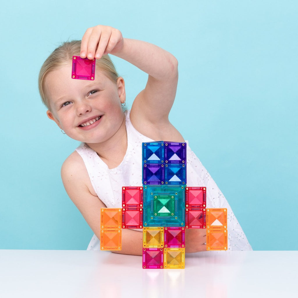 Girl adding a pink tile to a rainbow robot built with CONNETIX portal tiles