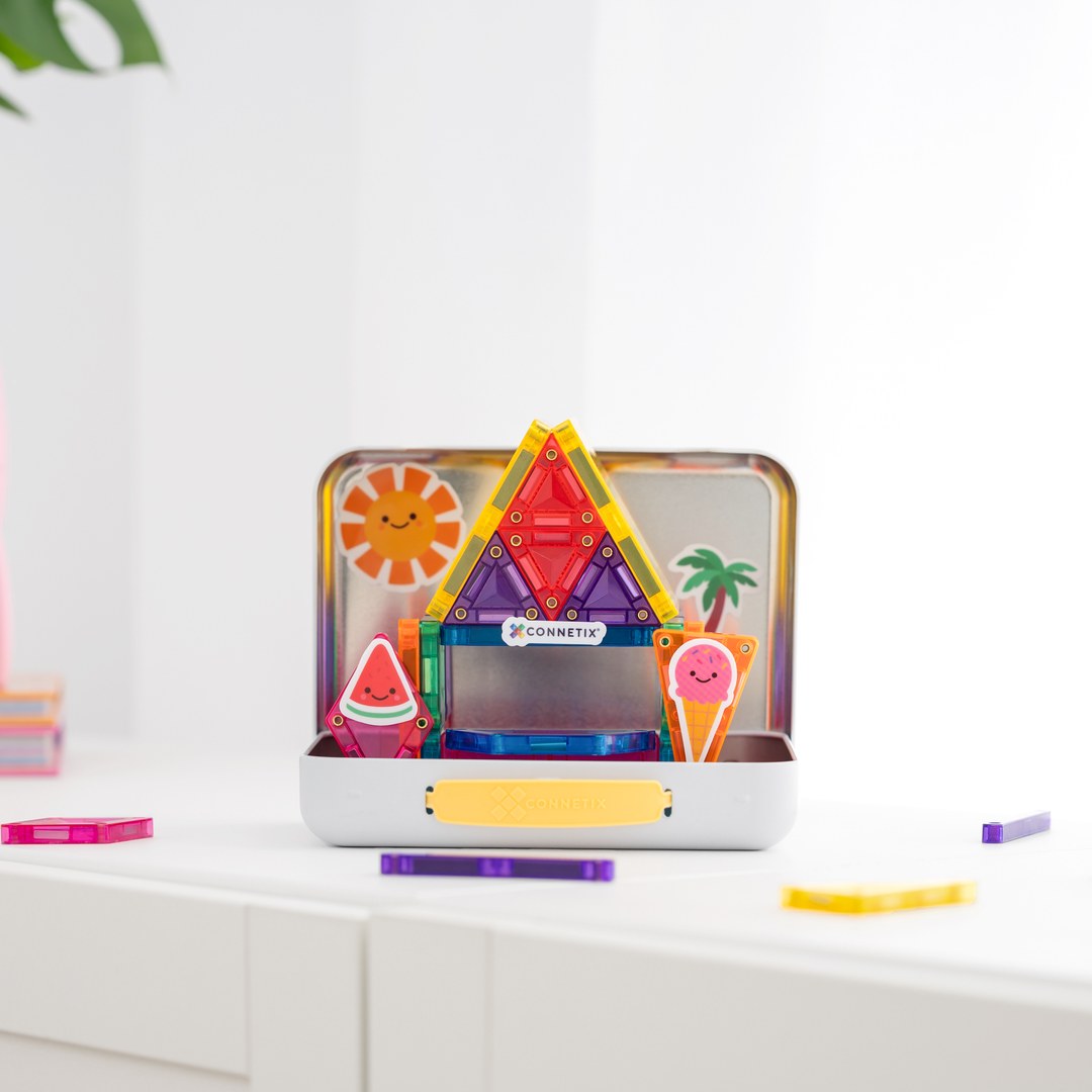 Excited boy beside a rainbow mini magnetic tile dinosaur built in the CONNETIX tin