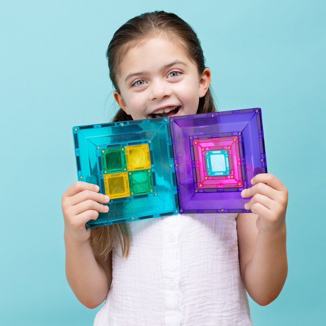 Excited girl holding two CONNETIX portal tiles with squares nested inside