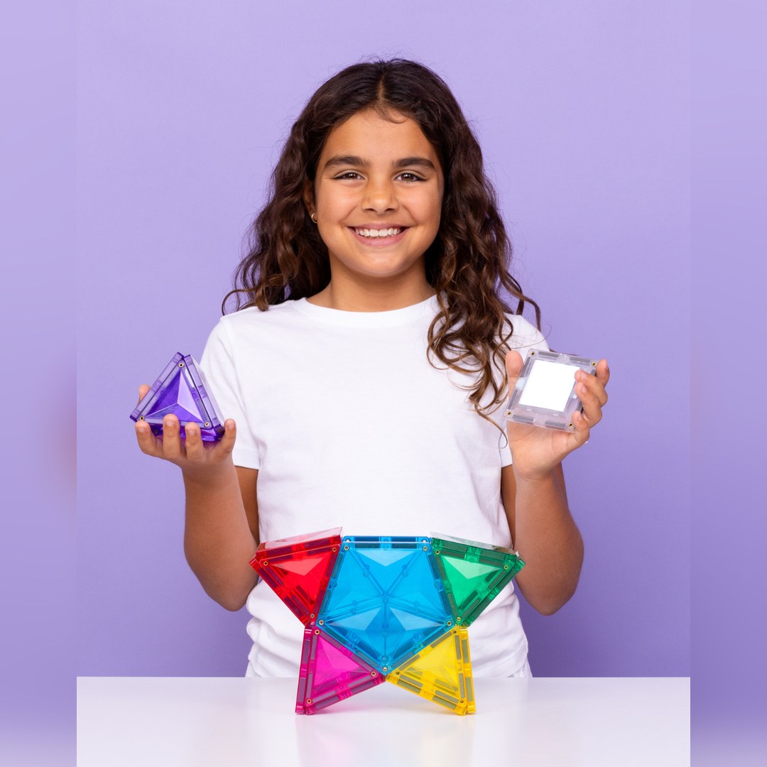 Girl holding a CONNETIX triangle pyramid and the rechargeable light-up tile beside a star build