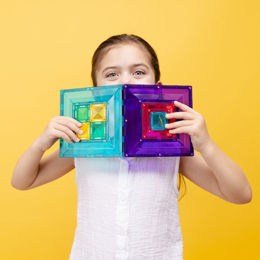 Girl peeking over teal and purple CONNETIX portal tiles with nested squares