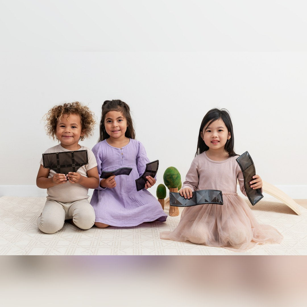Three children holding black CONNETIX road ramp and junction tiles