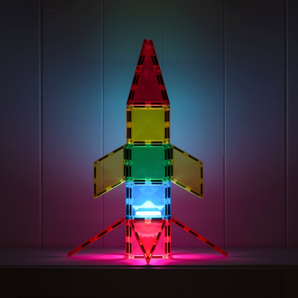 Rainbow CONNETIX magnetic tile rocket glowing pink and blue from the light-up tile at night
