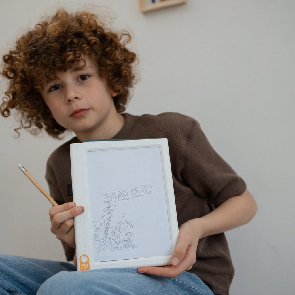 Child holding up the KIDYDRAW light pad with a traced Meli Melo drawing and a pencil