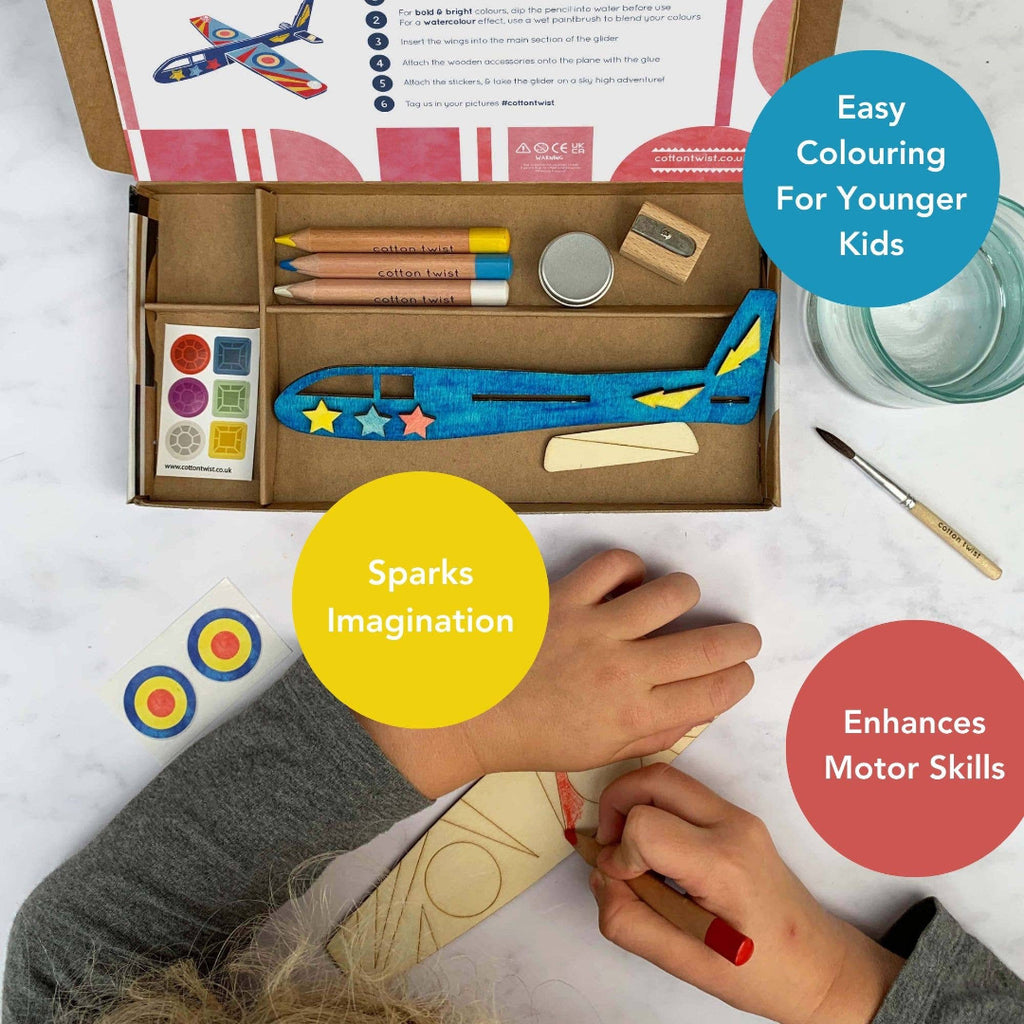 Children's craft kit with colouring book, crayons, and airplane model on a white surface.