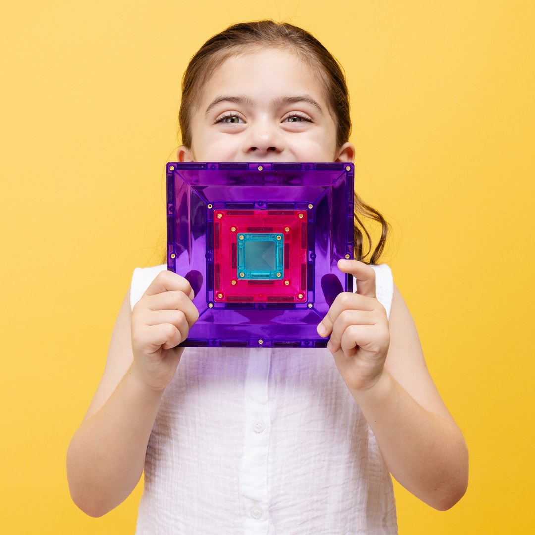 Smiling girl holding a purple CONNETIX portal tile with smaller tiles nested inside