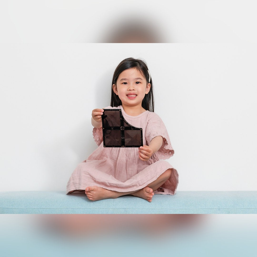 Smiling girl holding a black CONNETIX curved junction road tile