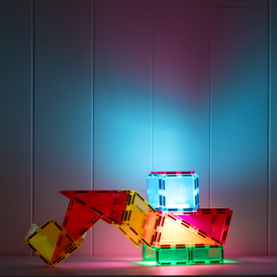 Cosmic creature built from CONNETIX magnetic tiles casting colourful light in a dark room