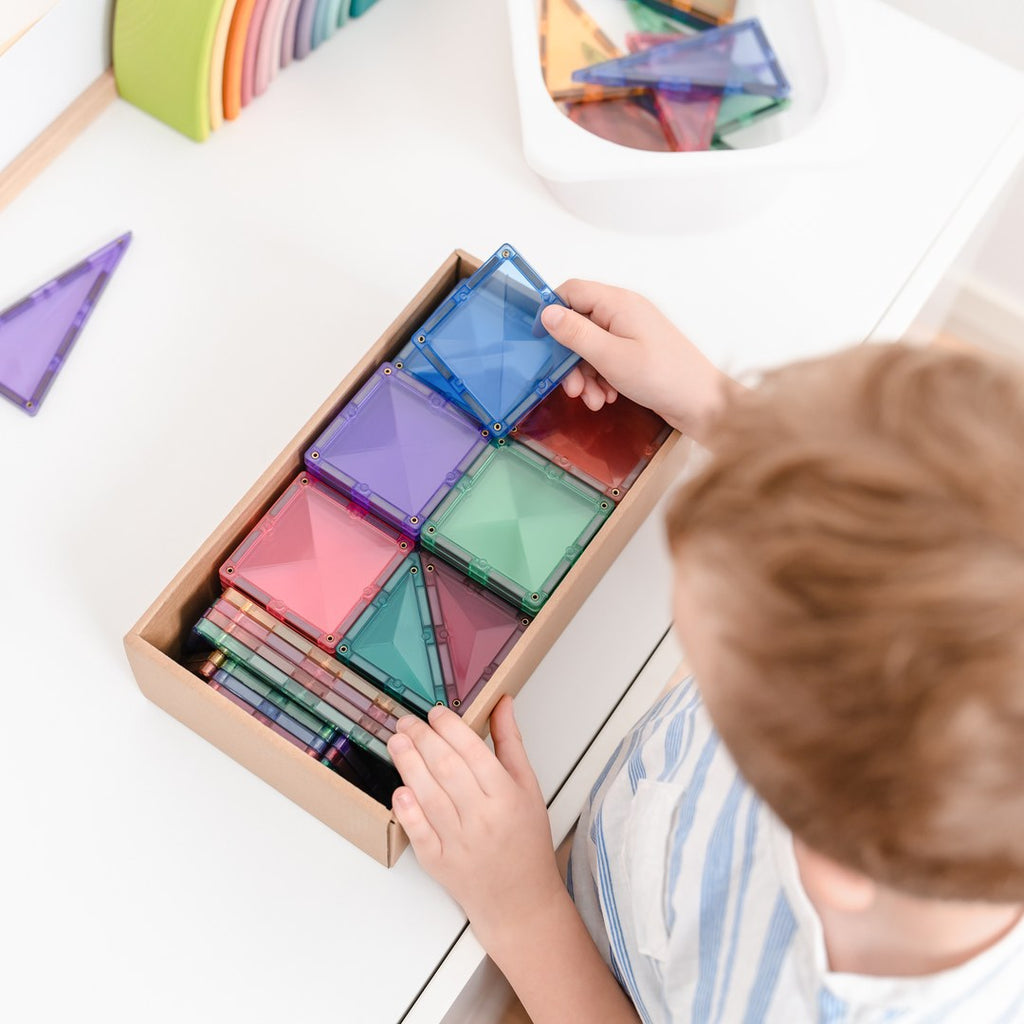 Child packing pastel CONNETIX magnetic tiles neatly into their box