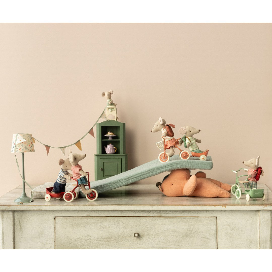 Maileg mice on tricycles and a ramp on top of a dresser with bunting and a mint cabinet