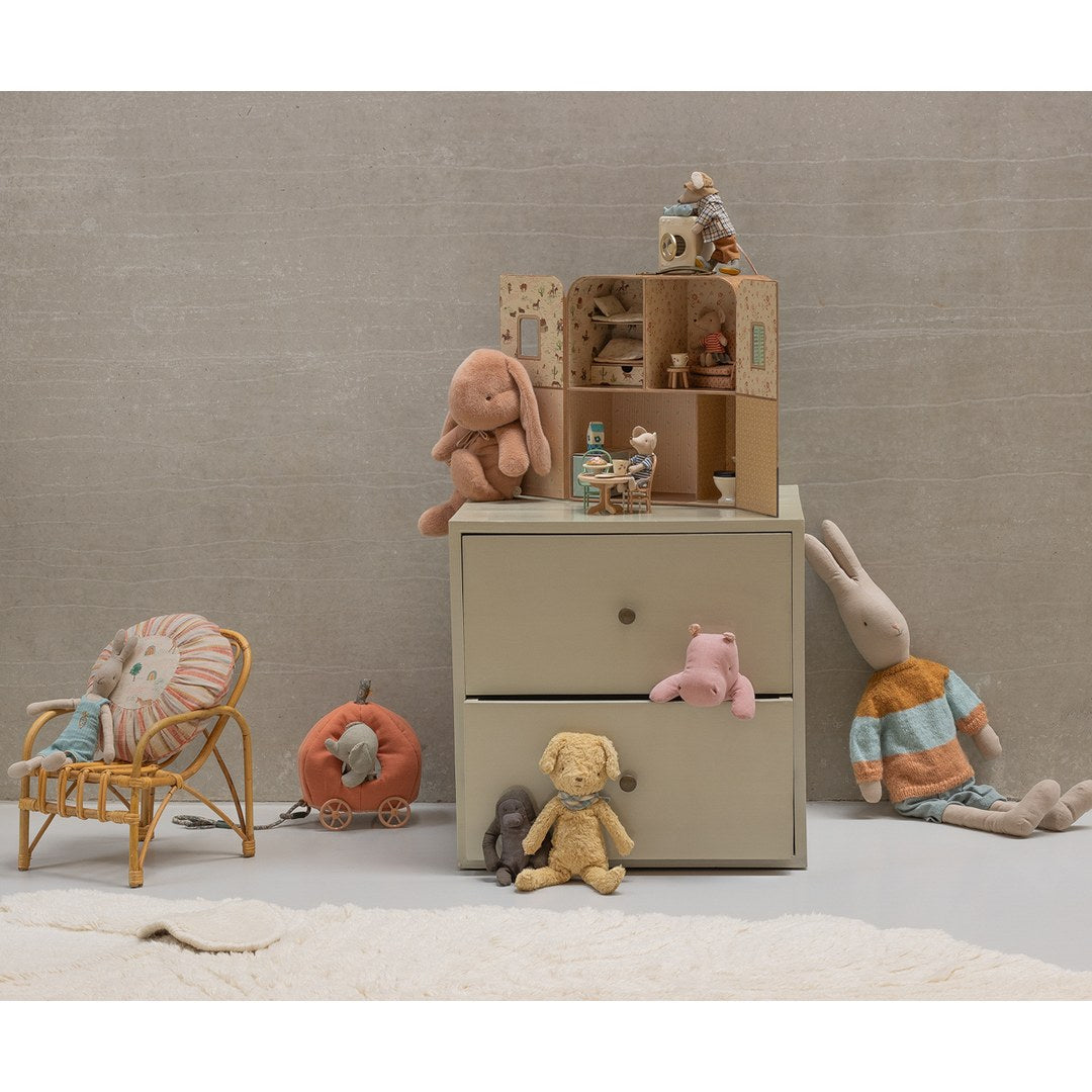 Maileg SuitCasa on top of a chest of drawers in a playroom with plush bunnies, a dog and a pumpkin carriage