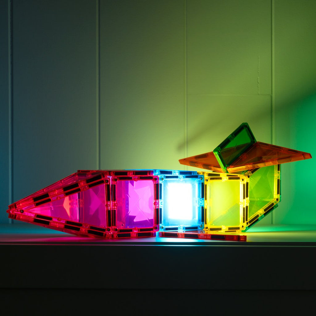 Glowing CONNETIX magnetic tile spaceship lighting the wall in pink, blue and green