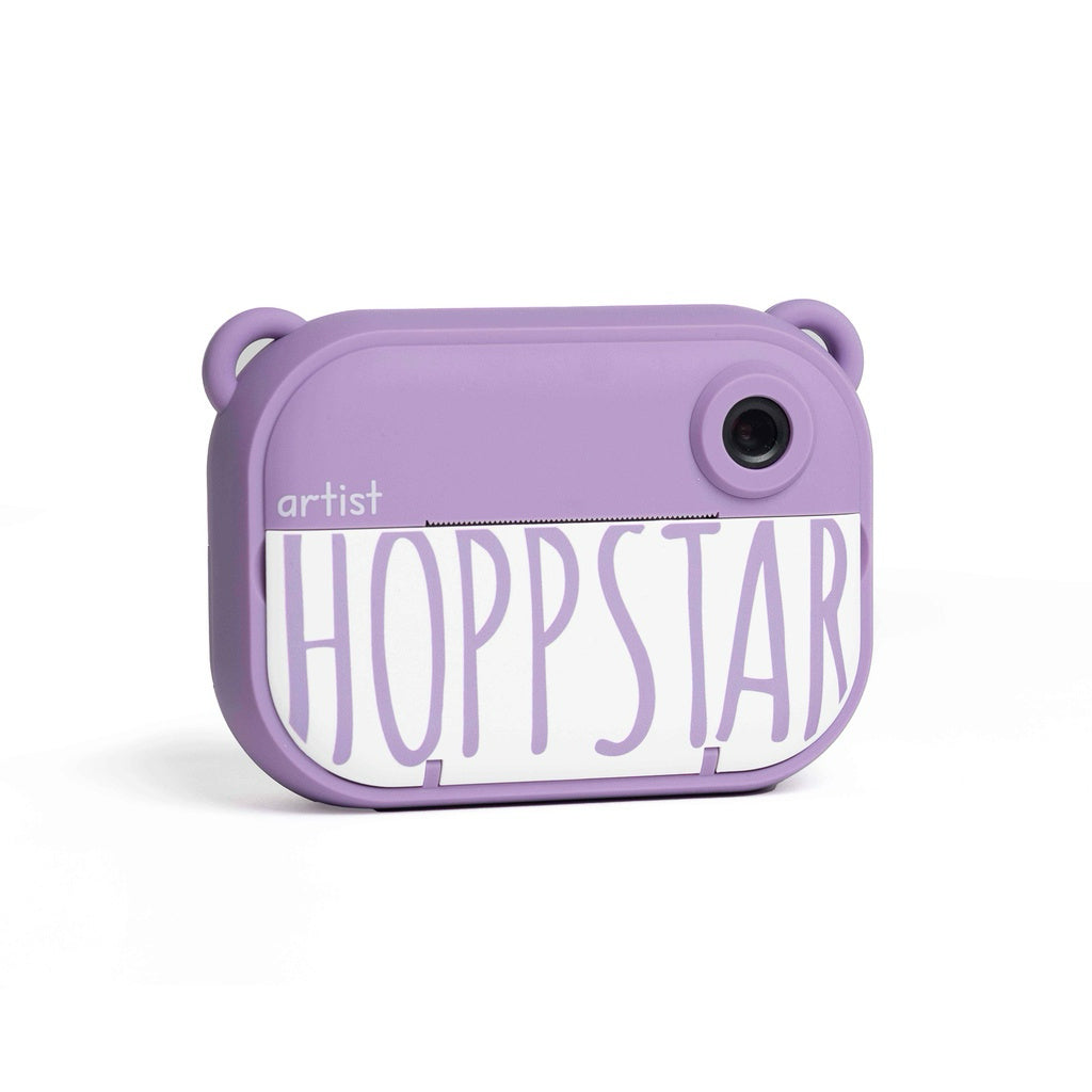 A lavender purple instant camera with a white front label reading 'artist HOPSTAR' in purple lettering, shown on a clean white background.