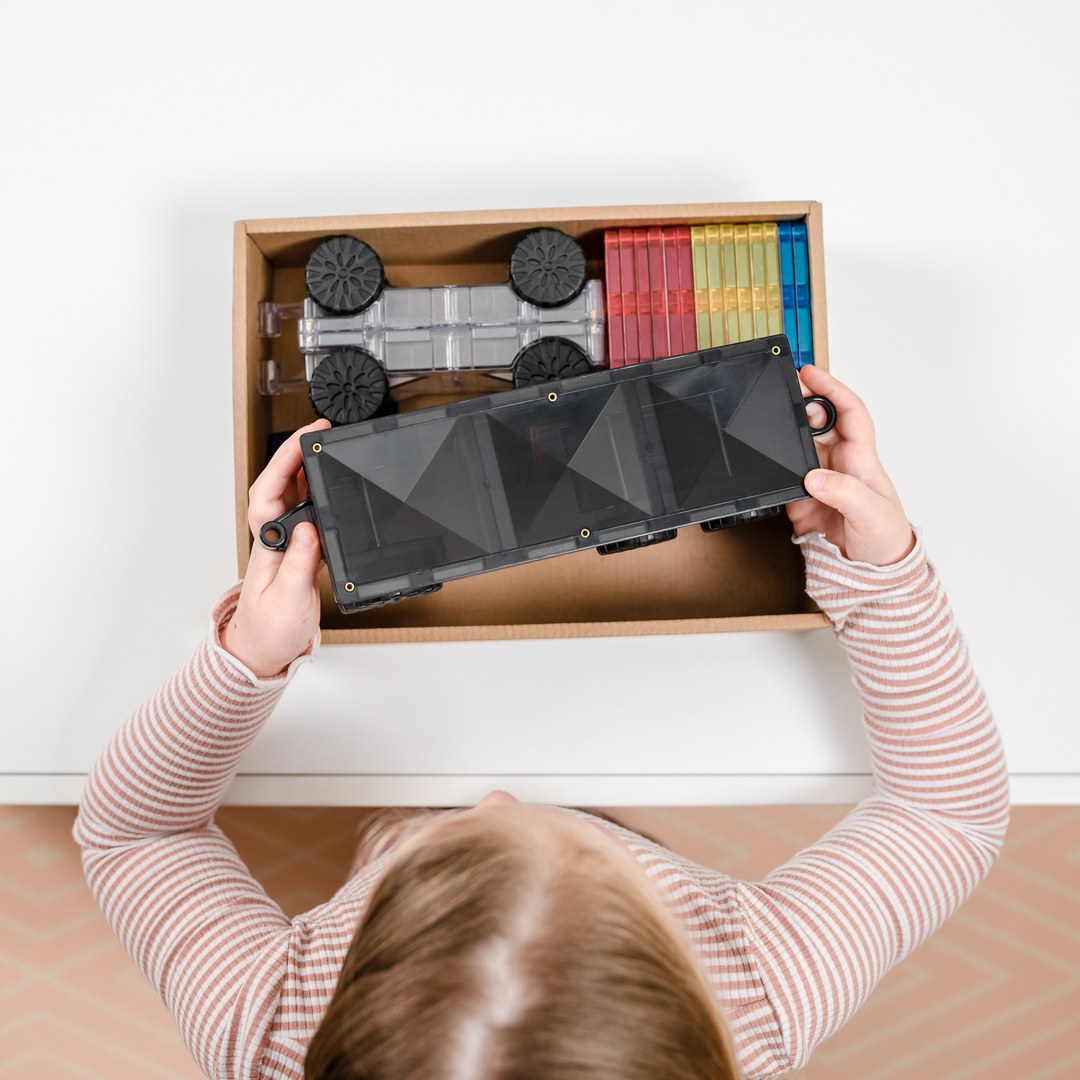 Child lifting the reversible CONNETIX motion base out of the box