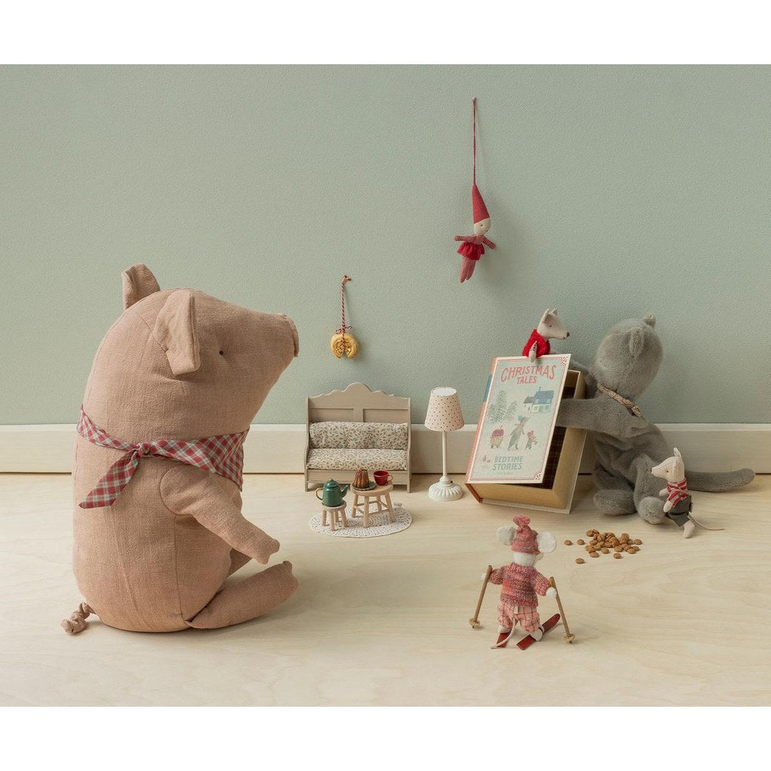 Maileg plush pig watching Christmas mice play with the book box, a mini sofa and skis
