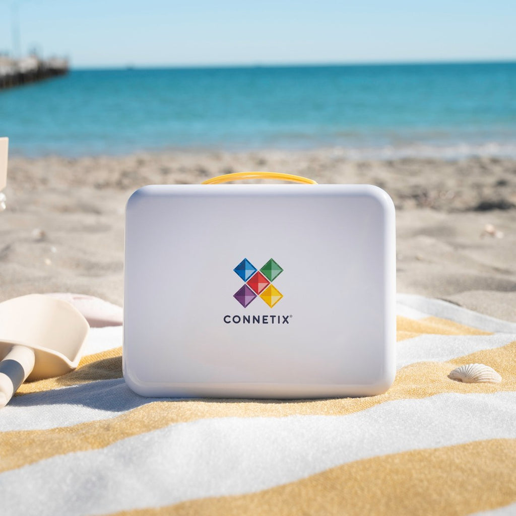 CONNETIX travel tin with yellow handle on a striped beach towel