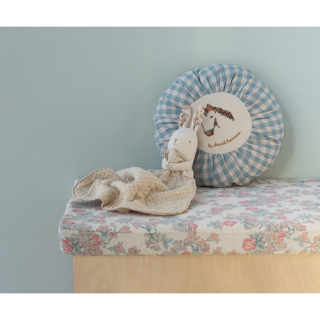 Maileg Lullaby Friends bunny on a floral bench in front of a blue gingham cushion