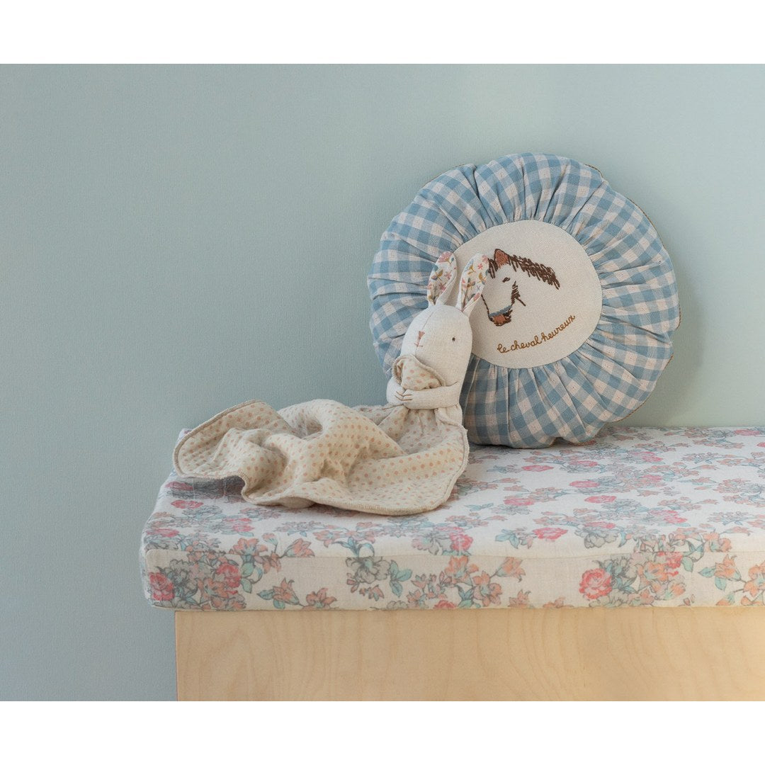 Maileg Lullaby Friends bunny on a floral bench in front of a blue gingham cushion