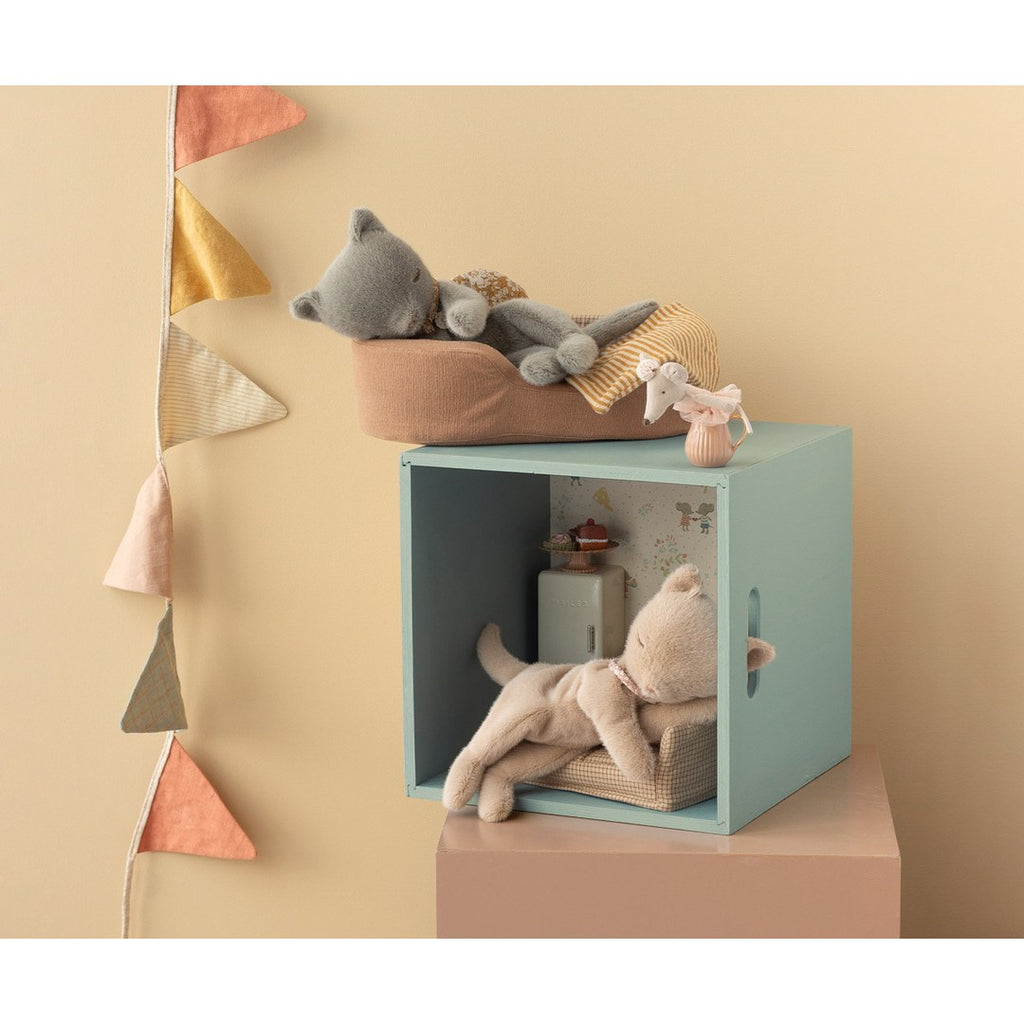 Maileg grey sleeping kitten in a basket on a mint box shelf with a cream kitten below and bunting