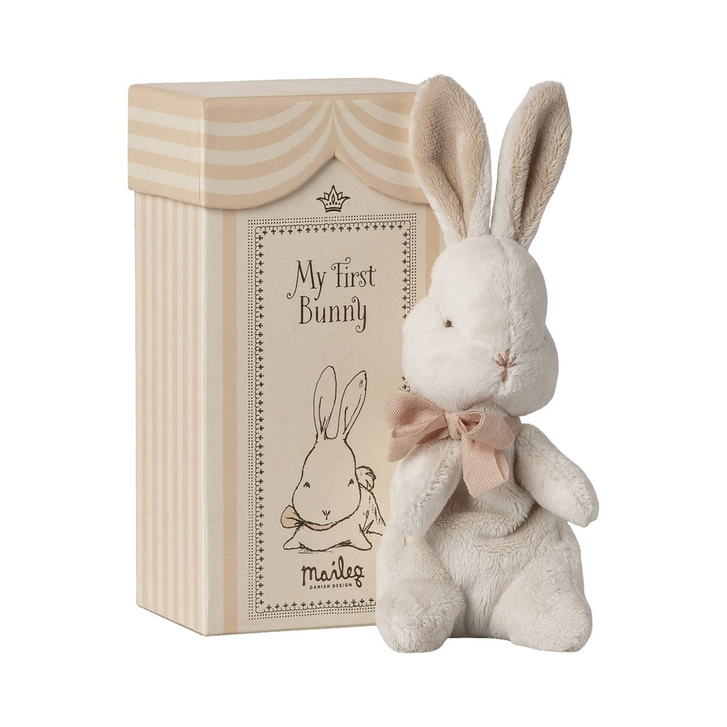 Maileg My First Bunny in powder with a pink bow, beside its striped gift box