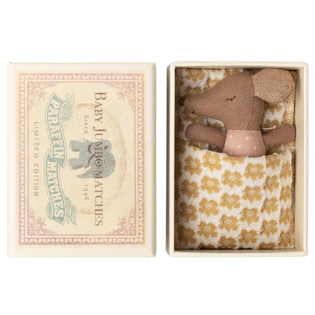 Maileg Sleepy Wakey baby mouse in rose polka dot romper tucked under a yellow floral blanket in an open Baby Jumbo matchbox, lid beside it