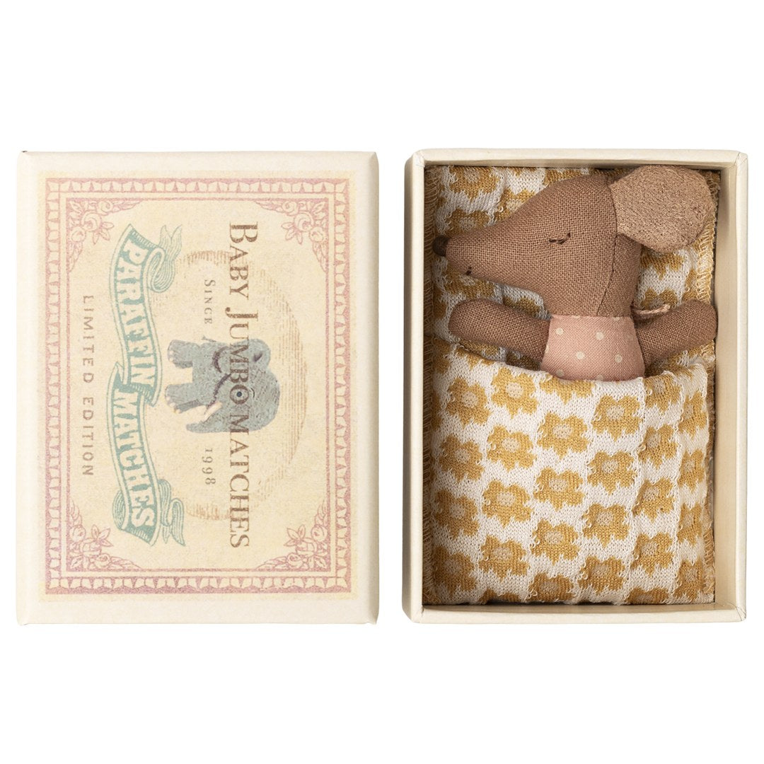Maileg Sleepy Wakey baby mouse in rose polka dot romper tucked under a yellow floral blanket in an open Baby Jumbo matchbox, lid beside it