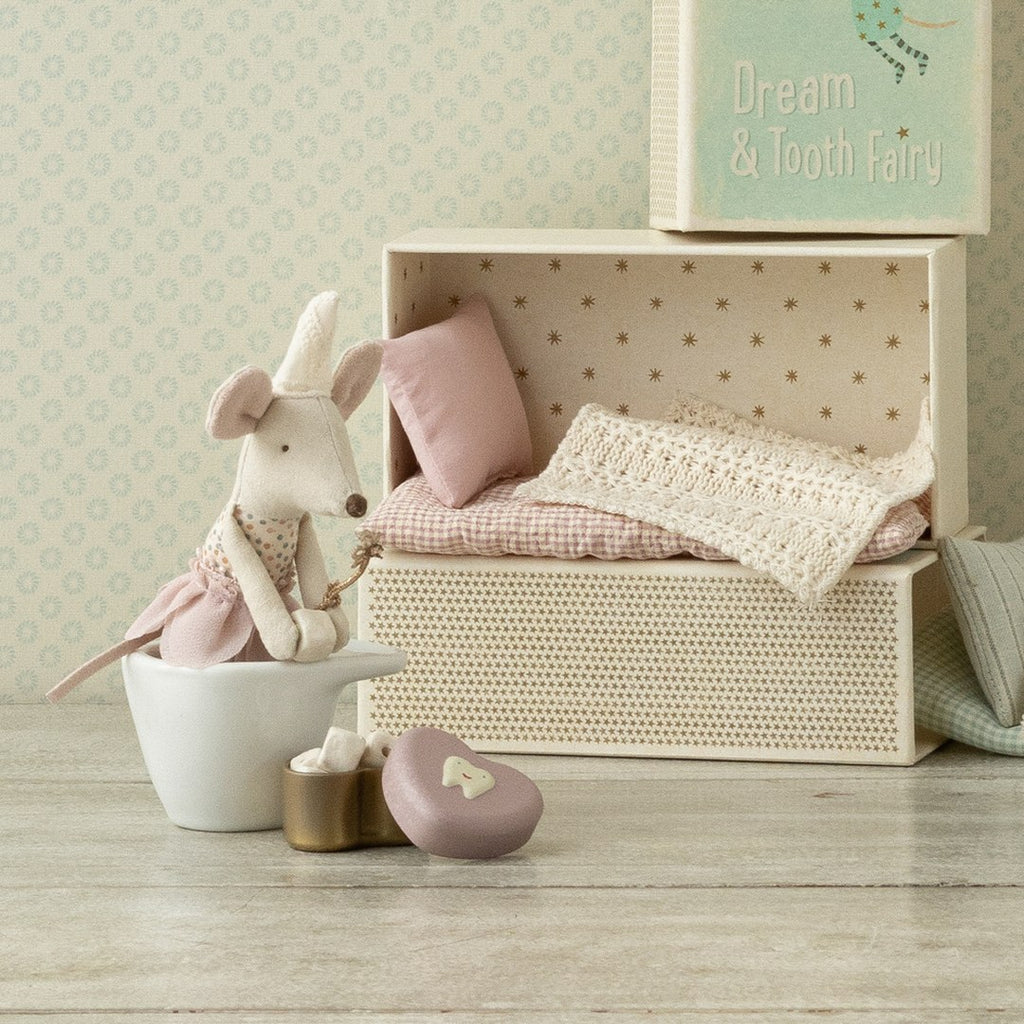 Maileg Tooth Fairy little sister mouse sitting in a white bowl beside her open matchbox bed with lace bedding and the heart tooth box