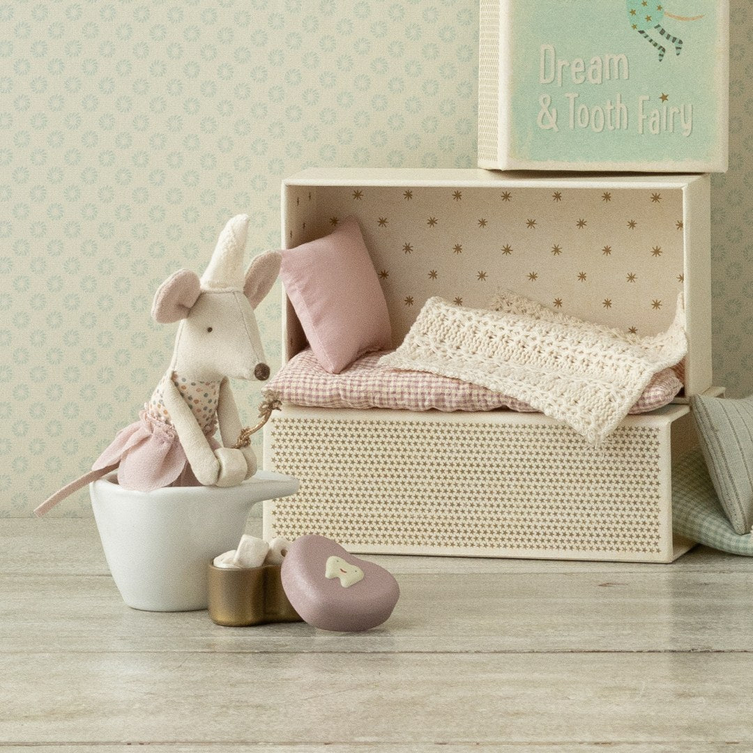 Maileg Tooth Fairy little sister mouse sitting in a white bowl beside her open matchbox bed with lace bedding and the heart tooth box