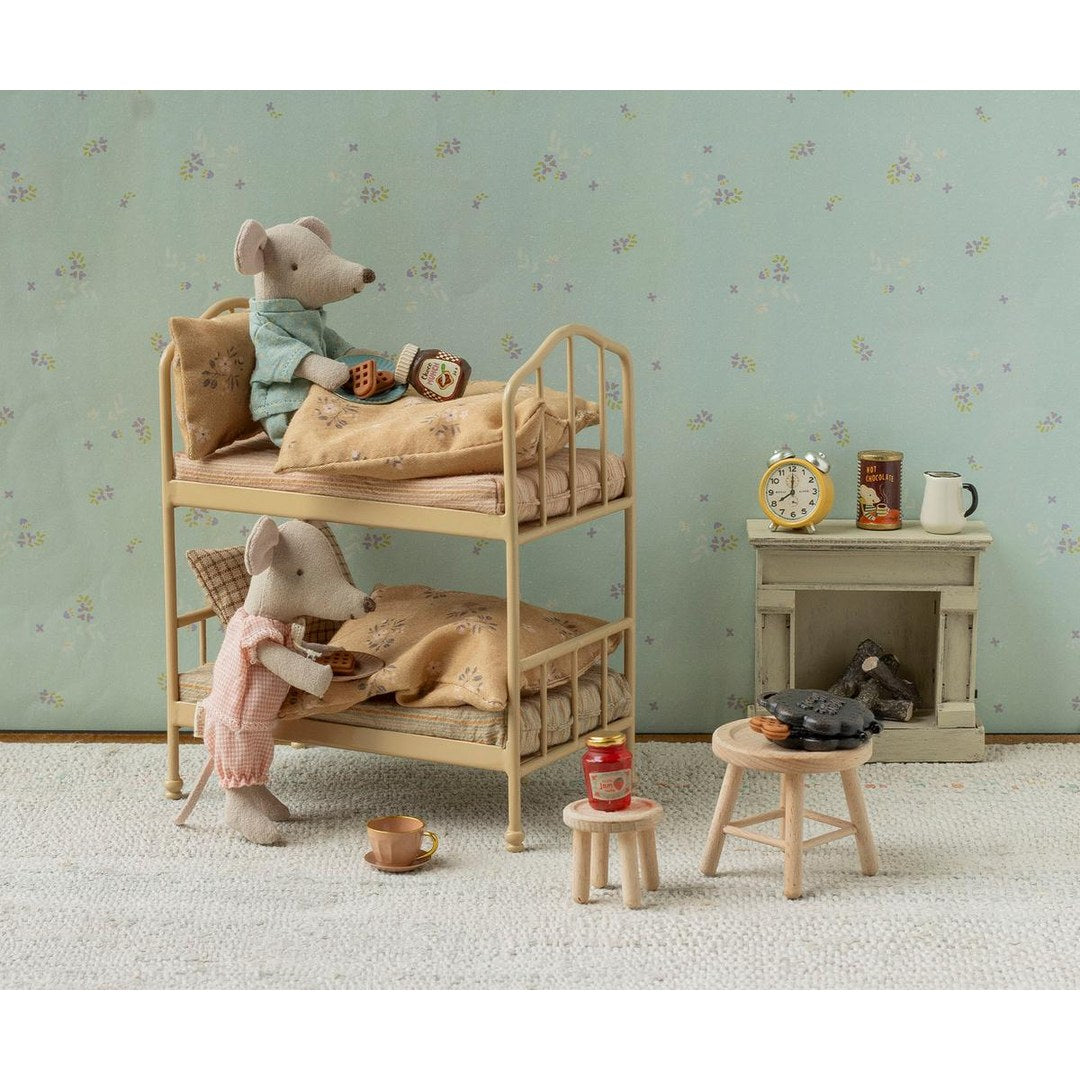 Maileg mice in pyjamas having breakfast on a wheat bunk bed with a fireplace and stools