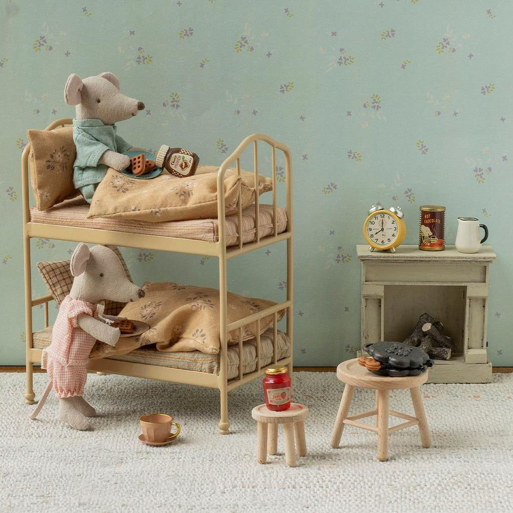 Maileg mice in pyjamas on a vintage metal bunk bed having breakfast, with a tiny fireplace, clock and wooden stools