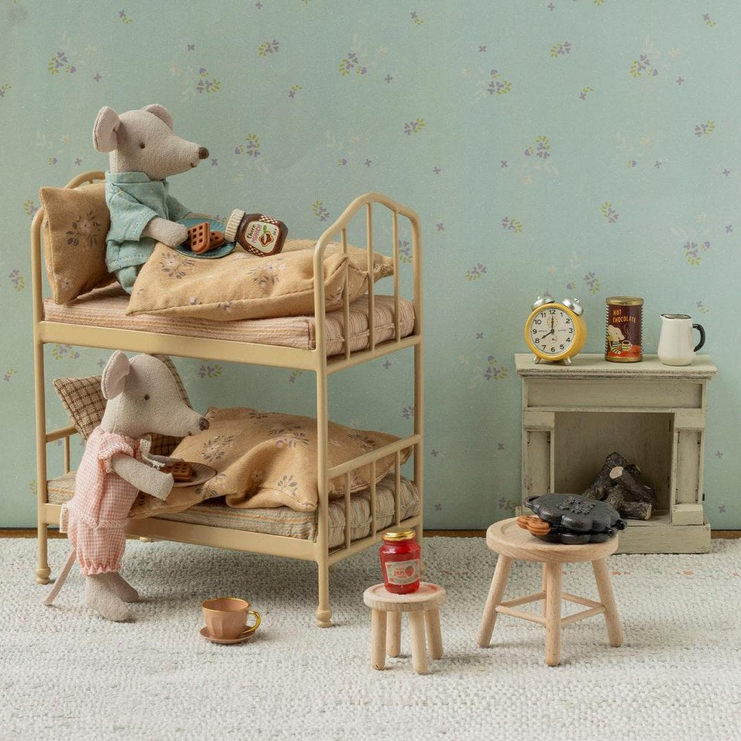 Maileg mice in pyjamas on a vintage metal bunk bed having breakfast, with a tiny fireplace, clock and wooden stools