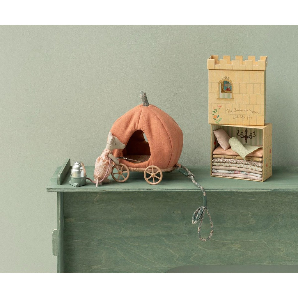 Maileg princess mouse pulling the pumpkin carriage across a green dresser beside the castle tower