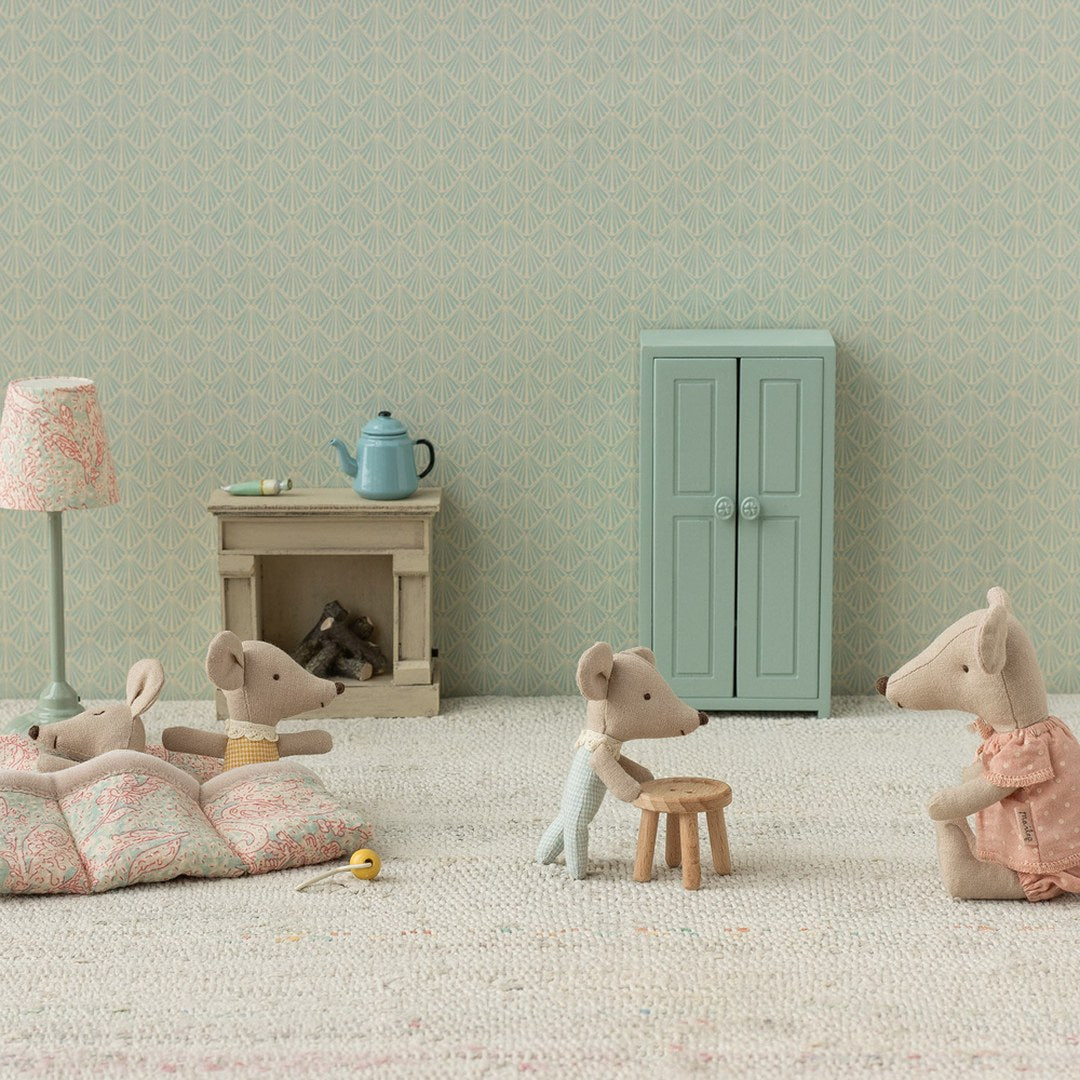 Maileg Triplets baby mice playing on a quilted mat with mum and big sister mice in a nursery with a mint cupboard and lamp