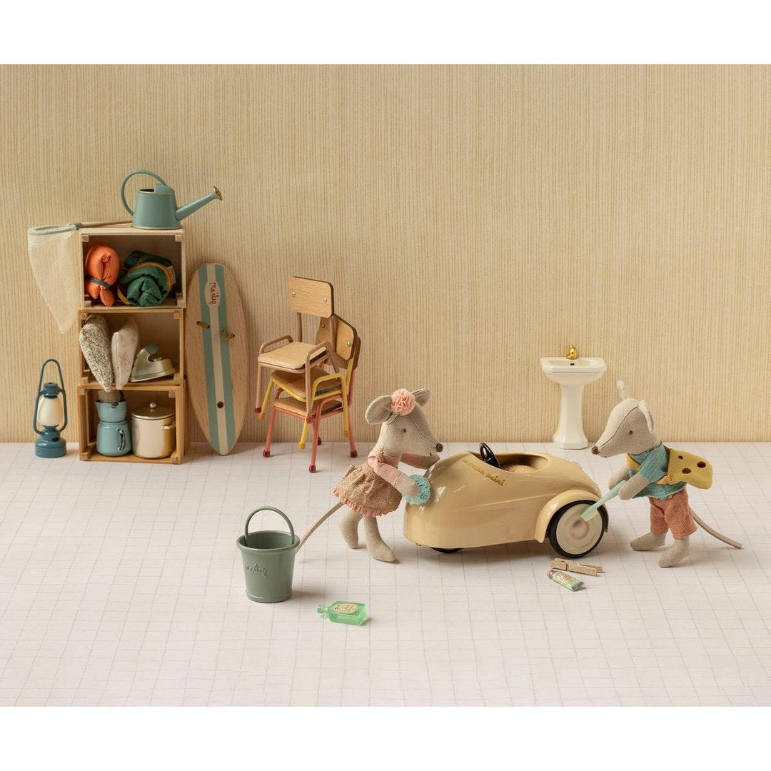 Maileg little sister and little brother mice washing a cream mouse car with a bucket and sponge, surfboard and shelf behind